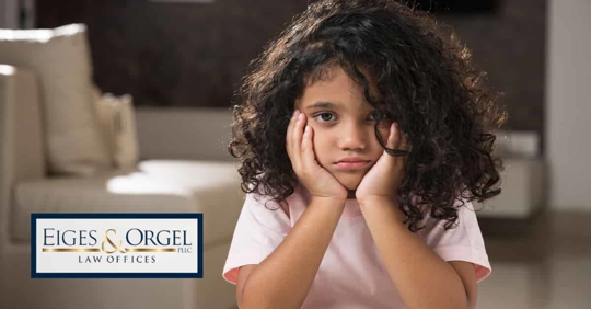 child with hands on face looking sad