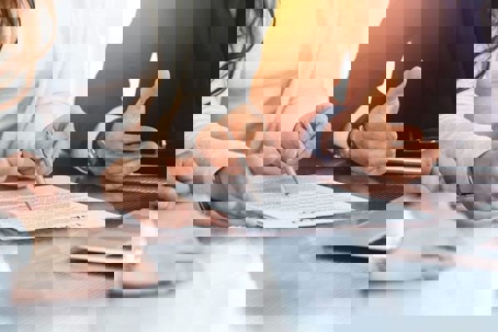 Three people in business attire reviewing and pointing at a contract on a desk