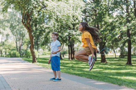 happy kids playing and jumping with skipping ropes in park