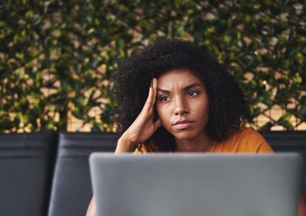 Contemplating young woman in cafe with laptop