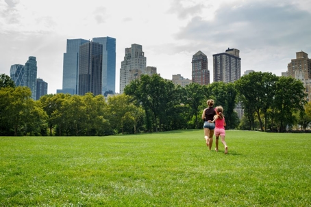 mother and daughter running away on the grass in the park